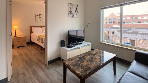 A living room with a couch , table , television and bed.