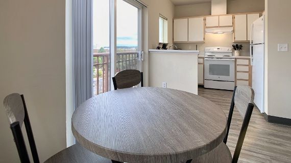 A kitchen with a table and chairs and a sliding glass door.
