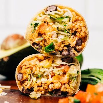 two burritos are stacked on top of each other on a wooden table 