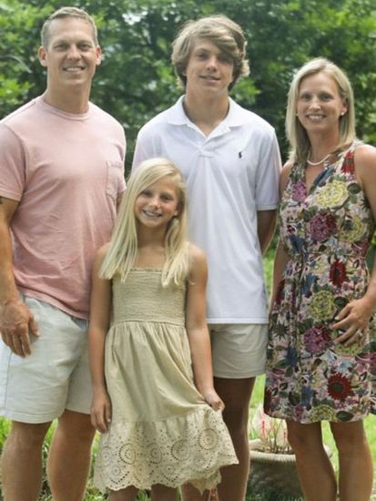 a family posing for a picture with the man wearing a pink shirt