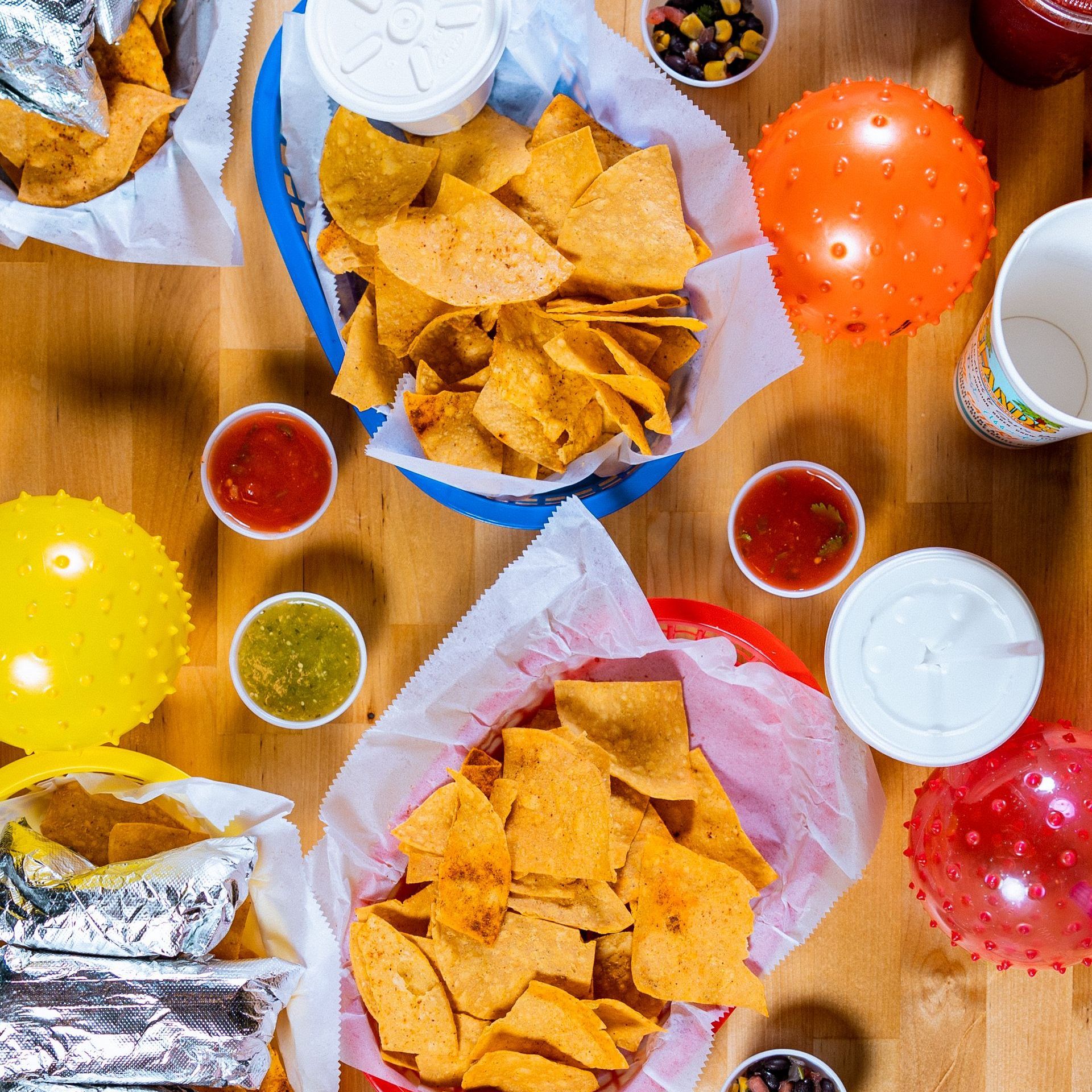 A wooden table topped with bowls of chips and salsa