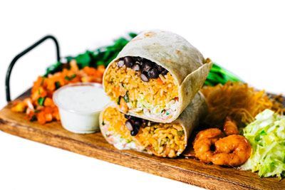 shrimp burrito with rice sitting on a wooden cutting board