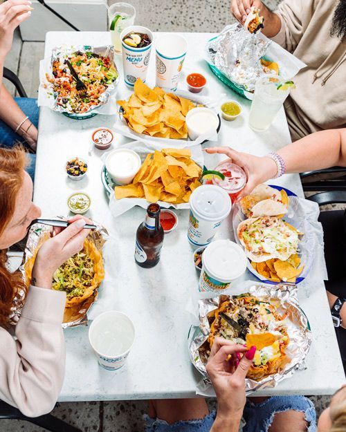 a group of people are sitting at a table eating mexican food .