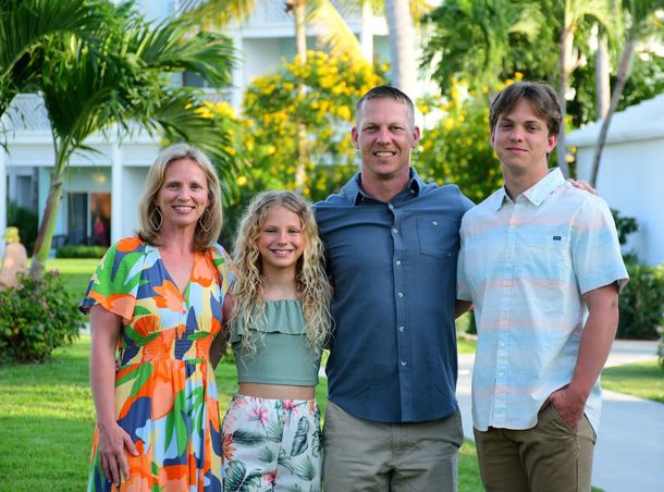 a family posing for a picture with the man wearing a pink shirt