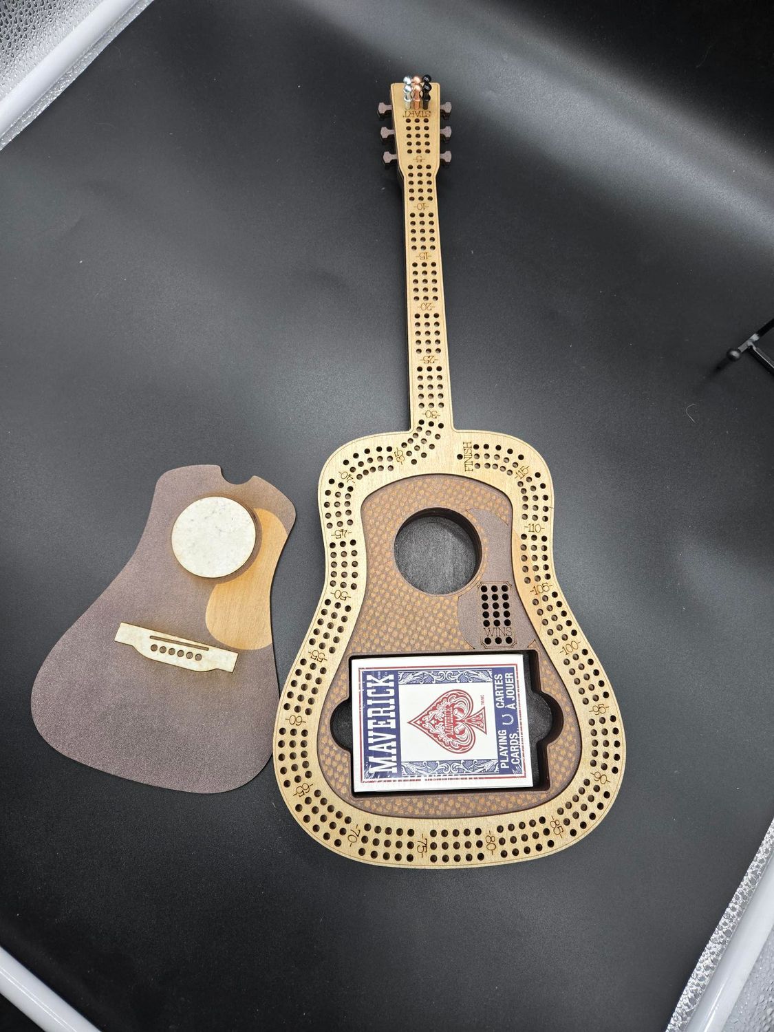 A disassembled wooden guitar-shaped box with a deck of cards inside and a separate back panel.