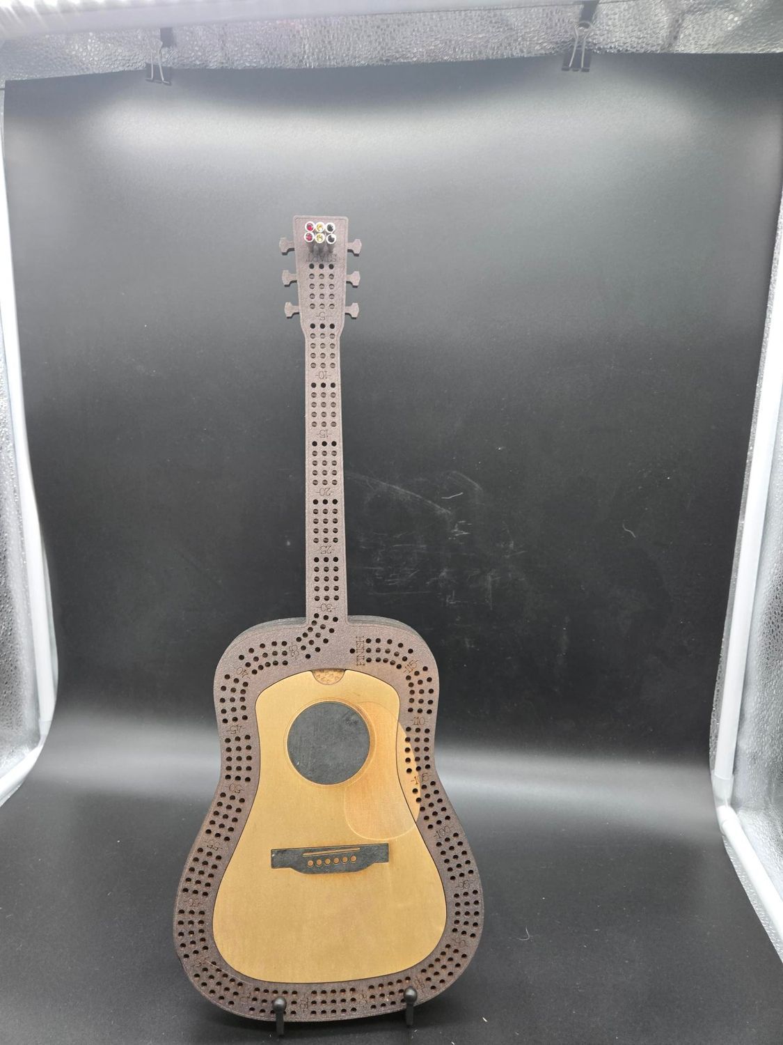 Wooden guitar-shaped cribbage board with brown and tan tones.