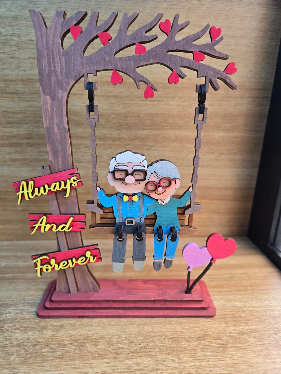 Wooden decorative piece of an elderly couple on a swing, with 