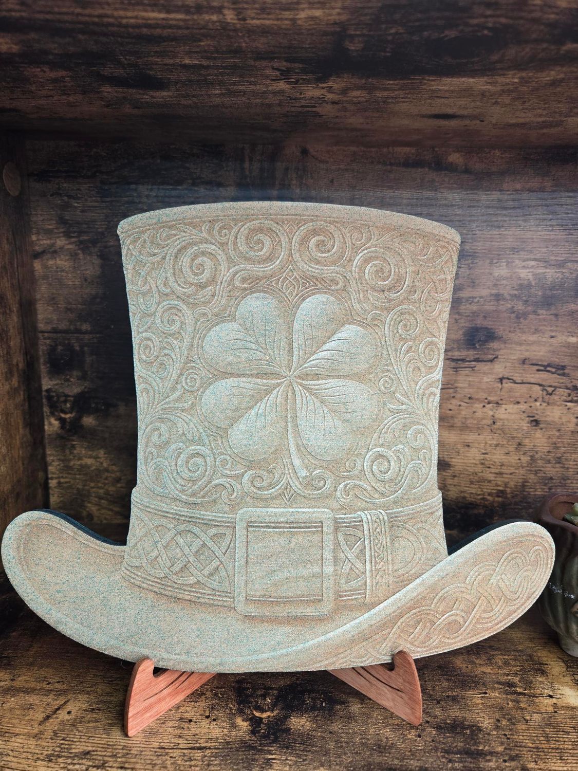 St. Patrick's Day leprechaun hat decoration with a four-leaf clover design, on a wooden stand.