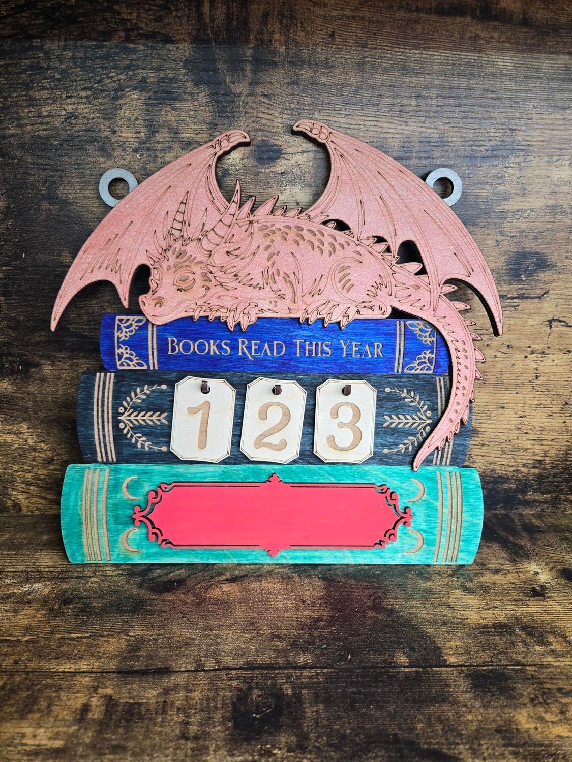 Wooden dragon-topped books-read counter. Blue, brown, and turquoise books, with 