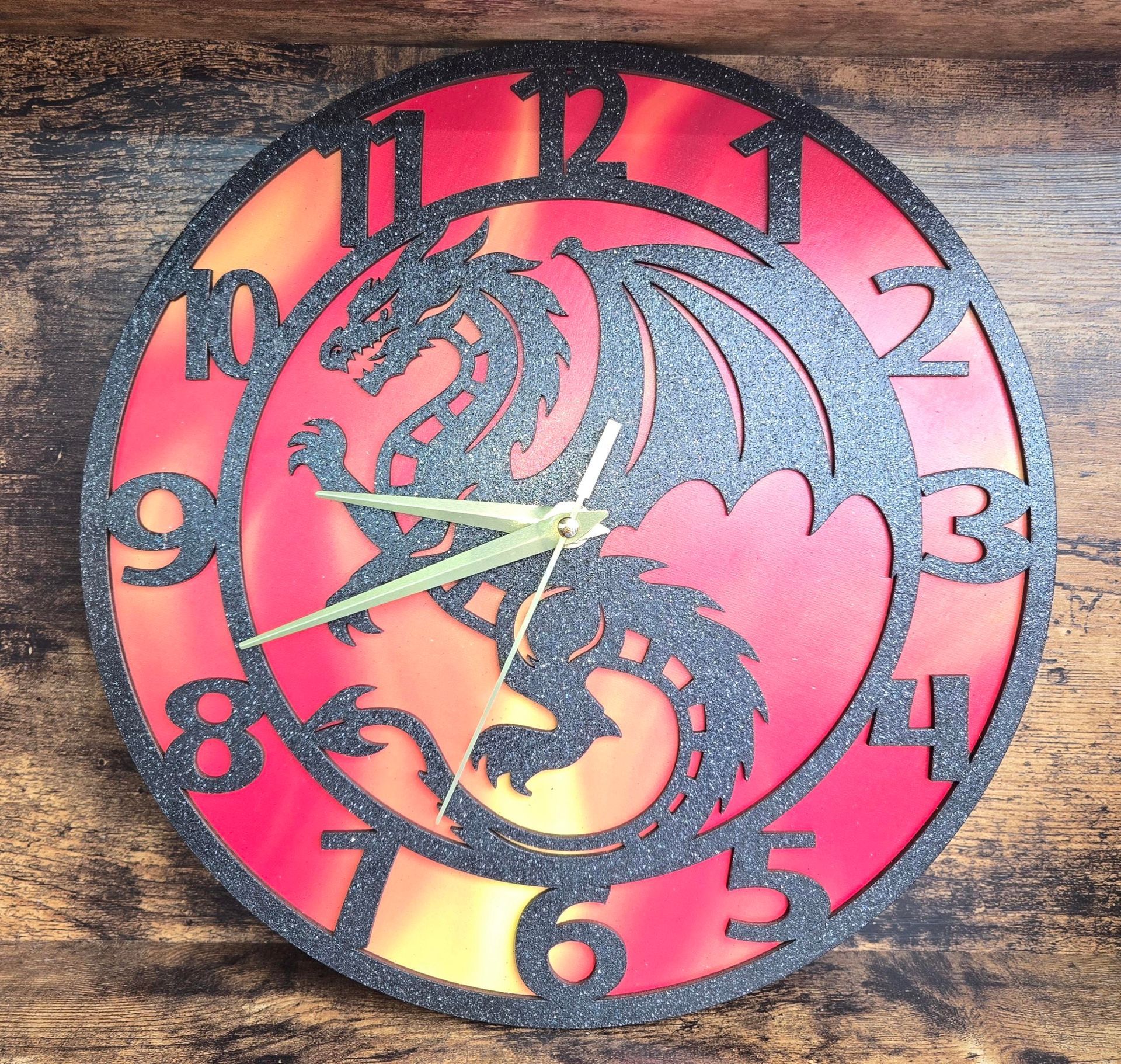 Dragon-themed wall clock with black, glittery frame and dragon silhouette over a red and orange gradient.
