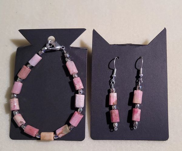 Pink stone bracelet and matching earrings on black display cards.