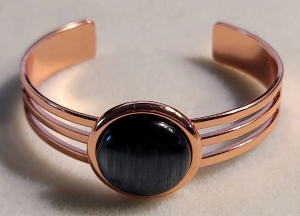 Copper bracelet with a round, dark stone.