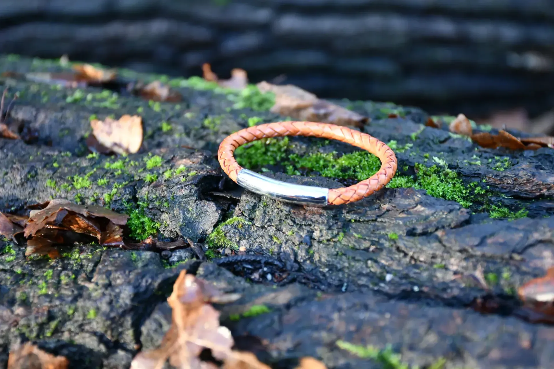 Een bruine gevlochten leren armband met een zilveren sluiting