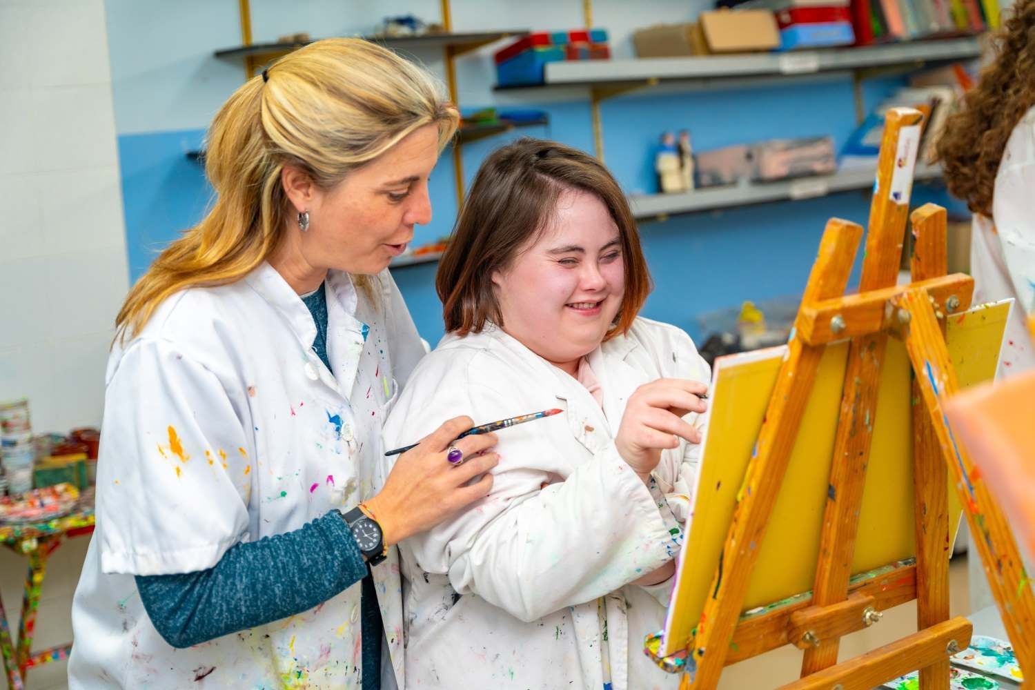 Teacher Helping A Smiling Woman With Down Syndrome During Painting Class — Eleos Support Services In Lavington, NSW