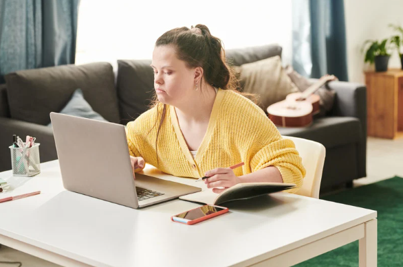 A Woman Sitting At A Desk Working On A Laptop — Eleos Support Services In Lavington, NSW