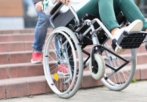 A Person in a Wheelchair is Being Pushed Up a Set of Stairs — Eleos Support Services In Lavington, NSW
