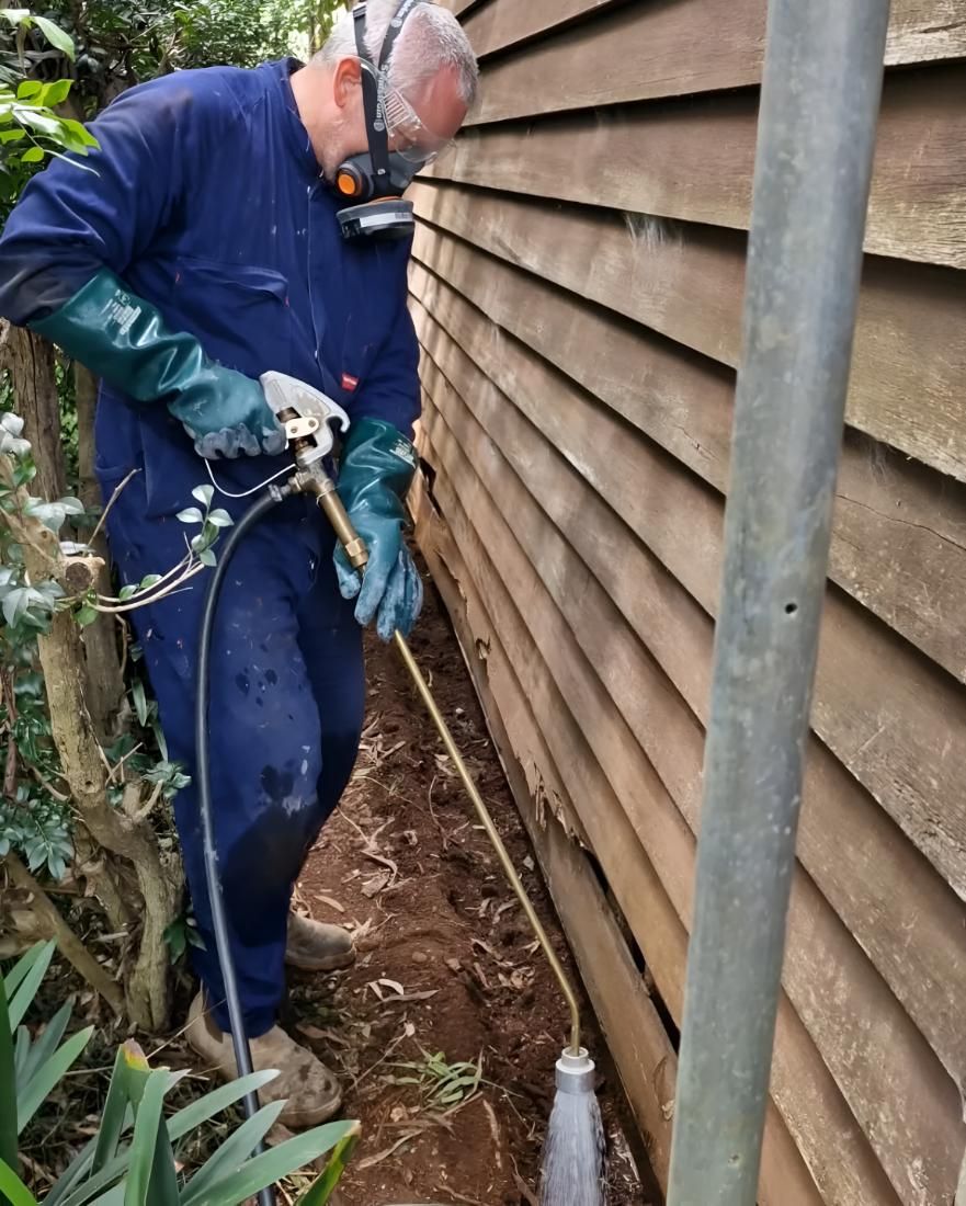 Man in a Blue Jumpsuit is Spraying on House — Shark Pest Control in Buderim, QLD