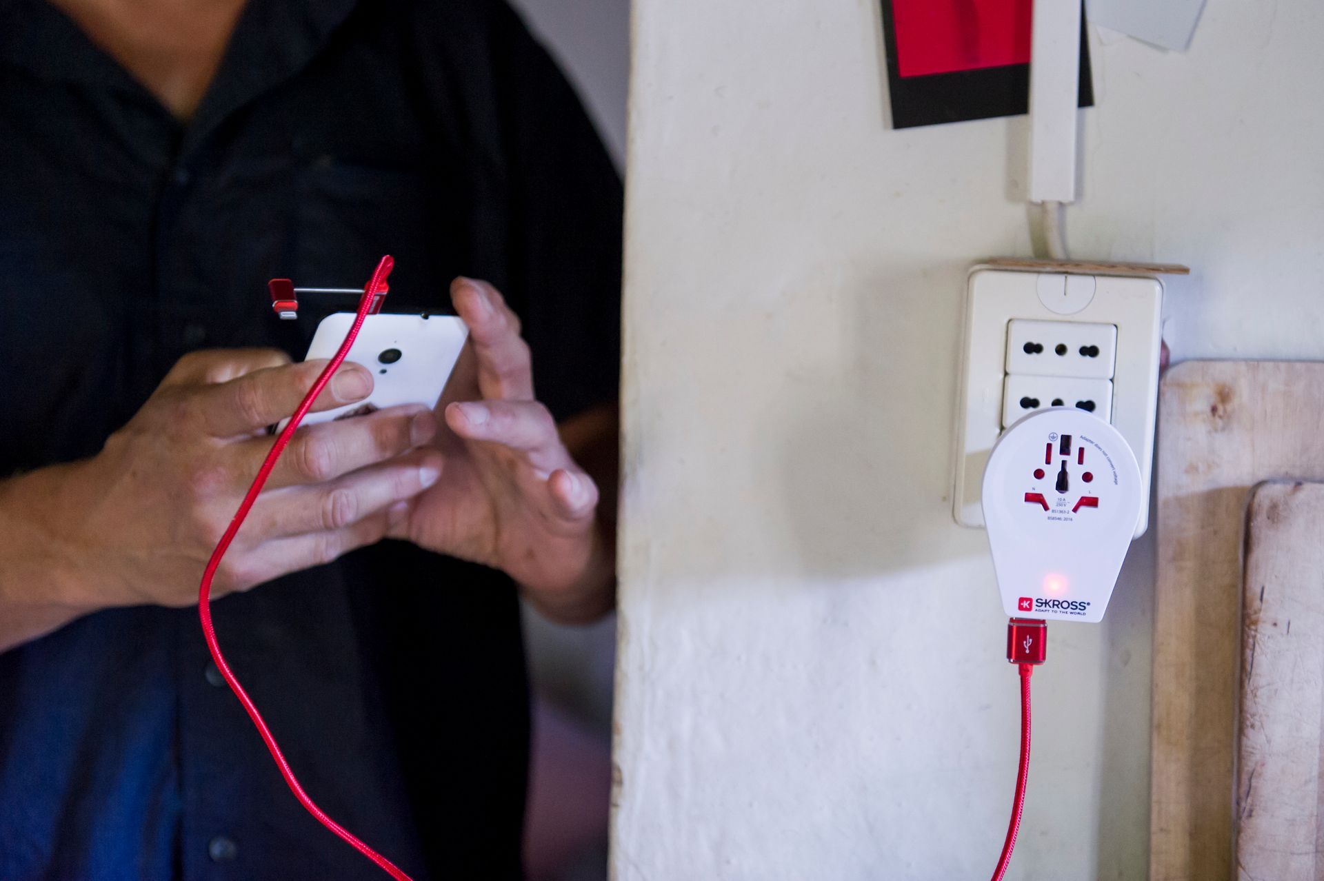 a person plugging a phone into a swiss Skross USB charger