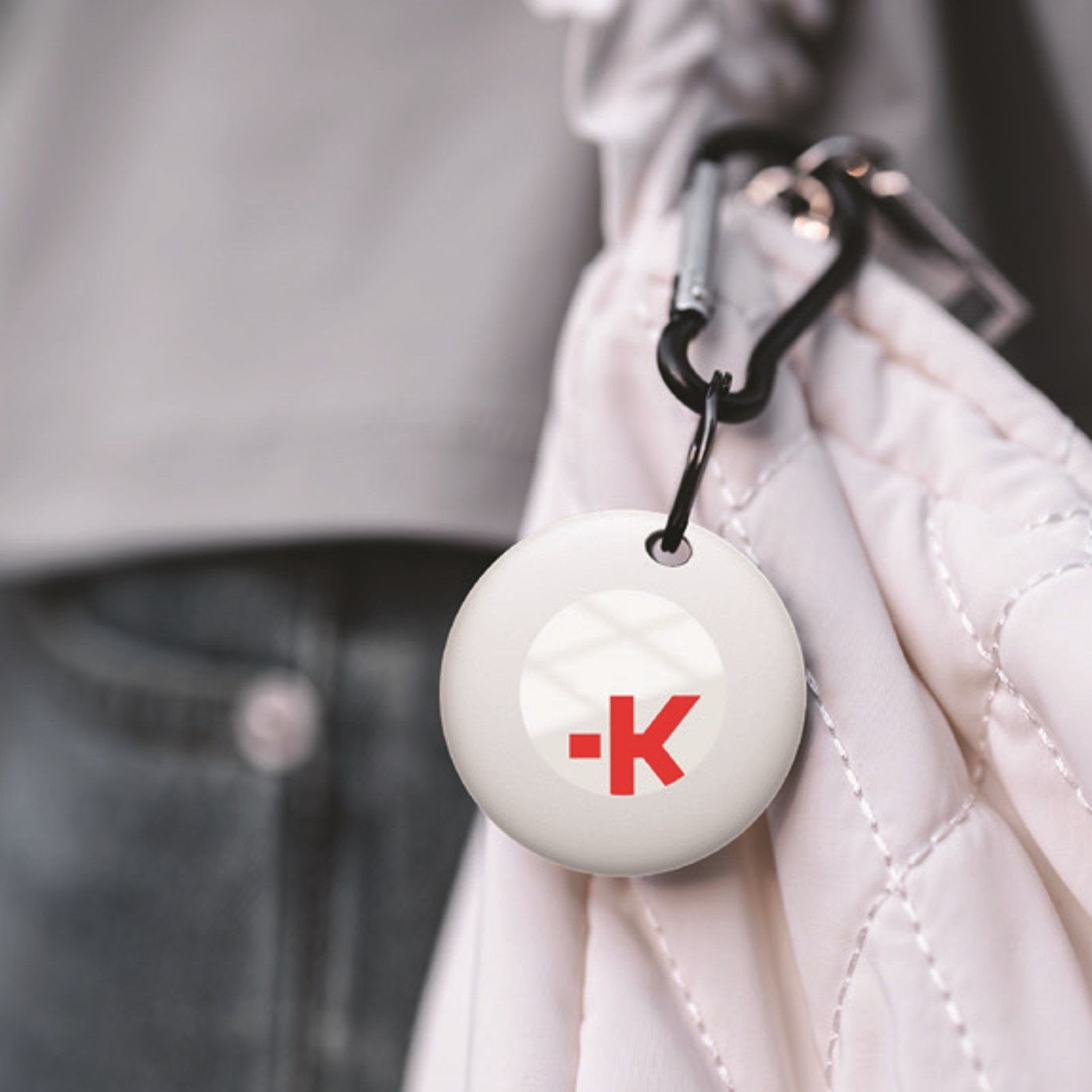 A white luggage tracker with the letter k on it