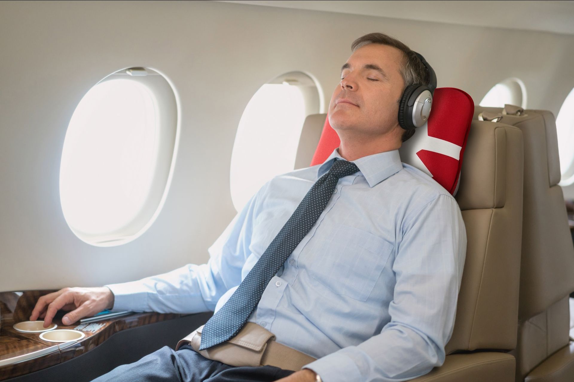 A man wearing headphones is sleeping on an airplane.
