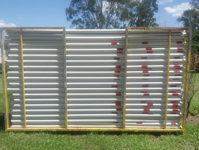 White Pipes Stacked in a Yellow Metal Frame on Grass — Jemal Enterprises In Finch Hatton, QLD