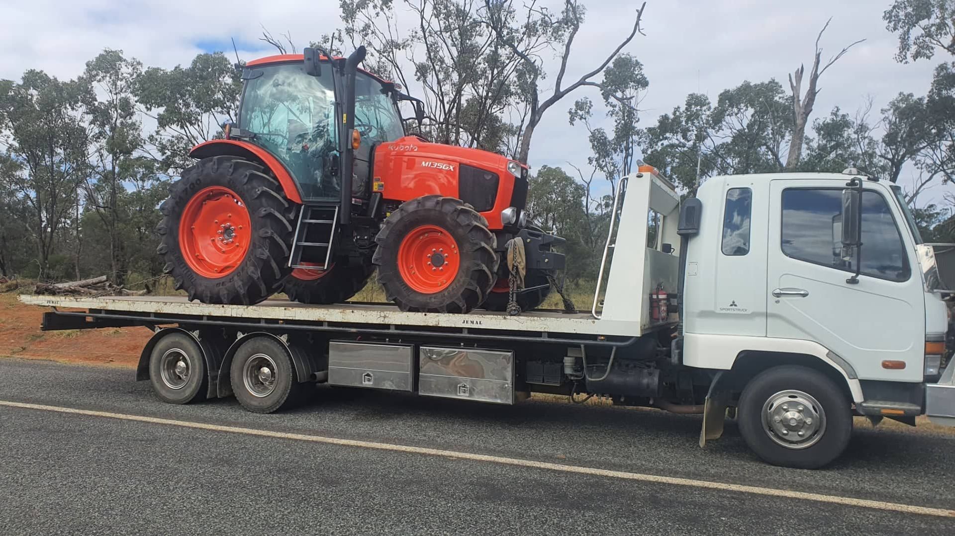 Orange Tractor on a Flatbed Truck, Traveling on a Road — Jemal Enterprises In Finch Hatton, QLD