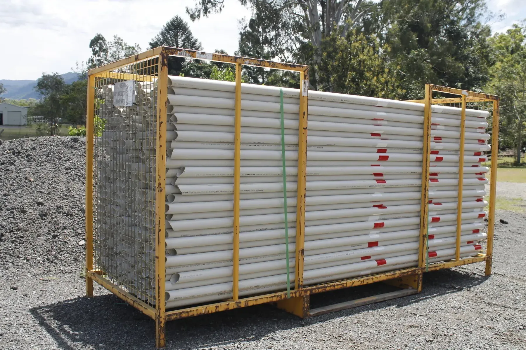 A Yellow Metal Cage Filled with White and Red Pvc Pipes, Outdoors on Gravel — Jemal Enterprises In Finch Hatton, QLD