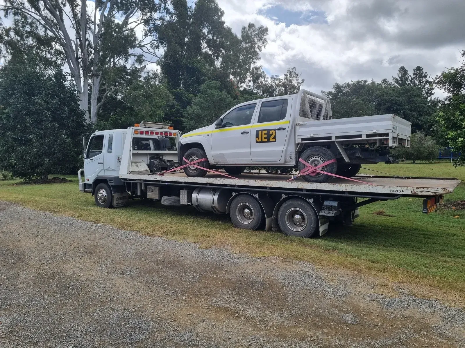 Tow Truck Carrying a White Pickup Truck on a Gravel Road, Outdoors — Jemal Enterprises In Finch Hatton, QLD