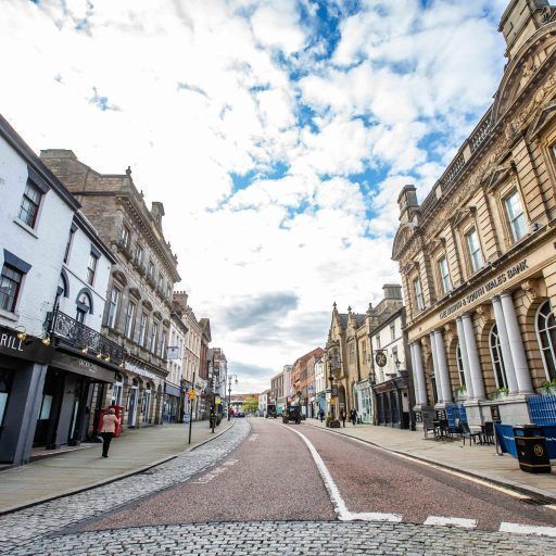 A cobblestone street in a city with a lot of buildings on both sides.