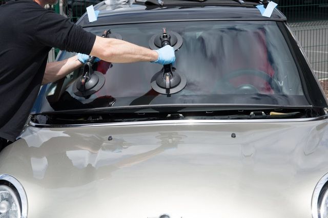 Technician using suction tools to replace a vehicle windshield.