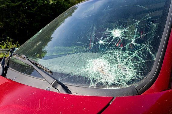 Damaged car windshield with large crack needing repair.