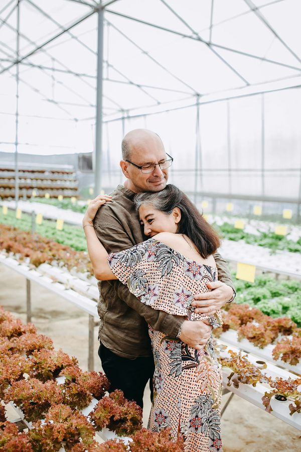 A man and a woman are hugging in a greenhouse.