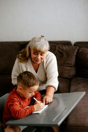 An elderly woman is helping a young boy with his homework.