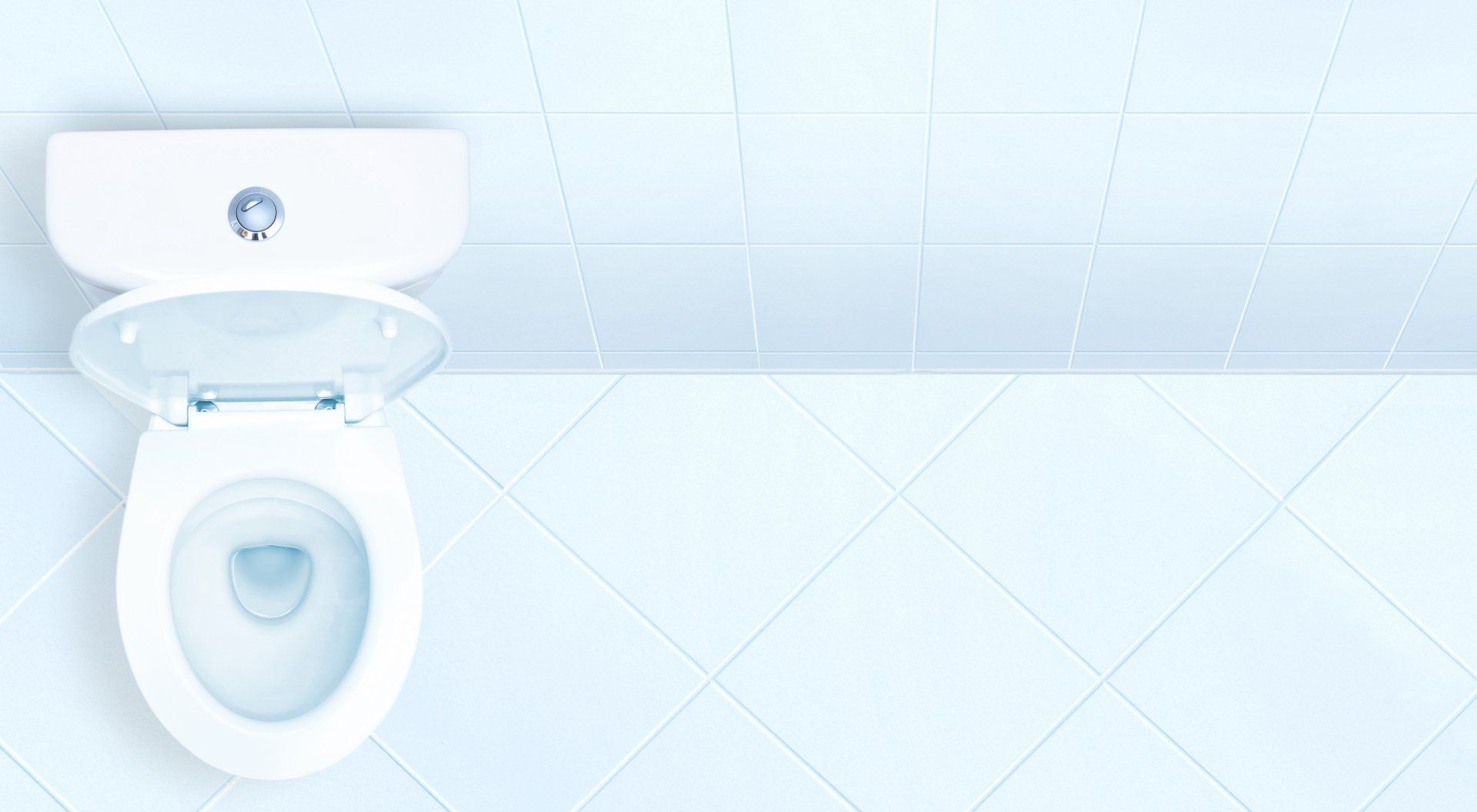 A white toilet is sitting on a tiled floor in a bathroom.