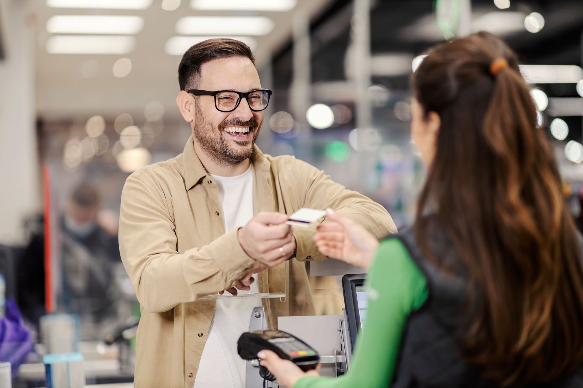 A man is giving a credit card to a woman in a store.