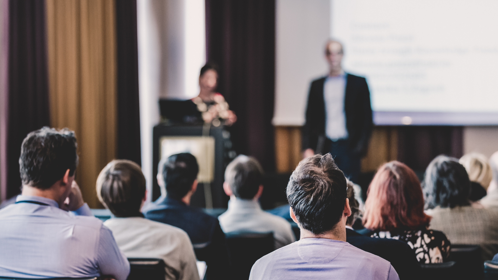 A group of people are sitting in a room watching a presentation.