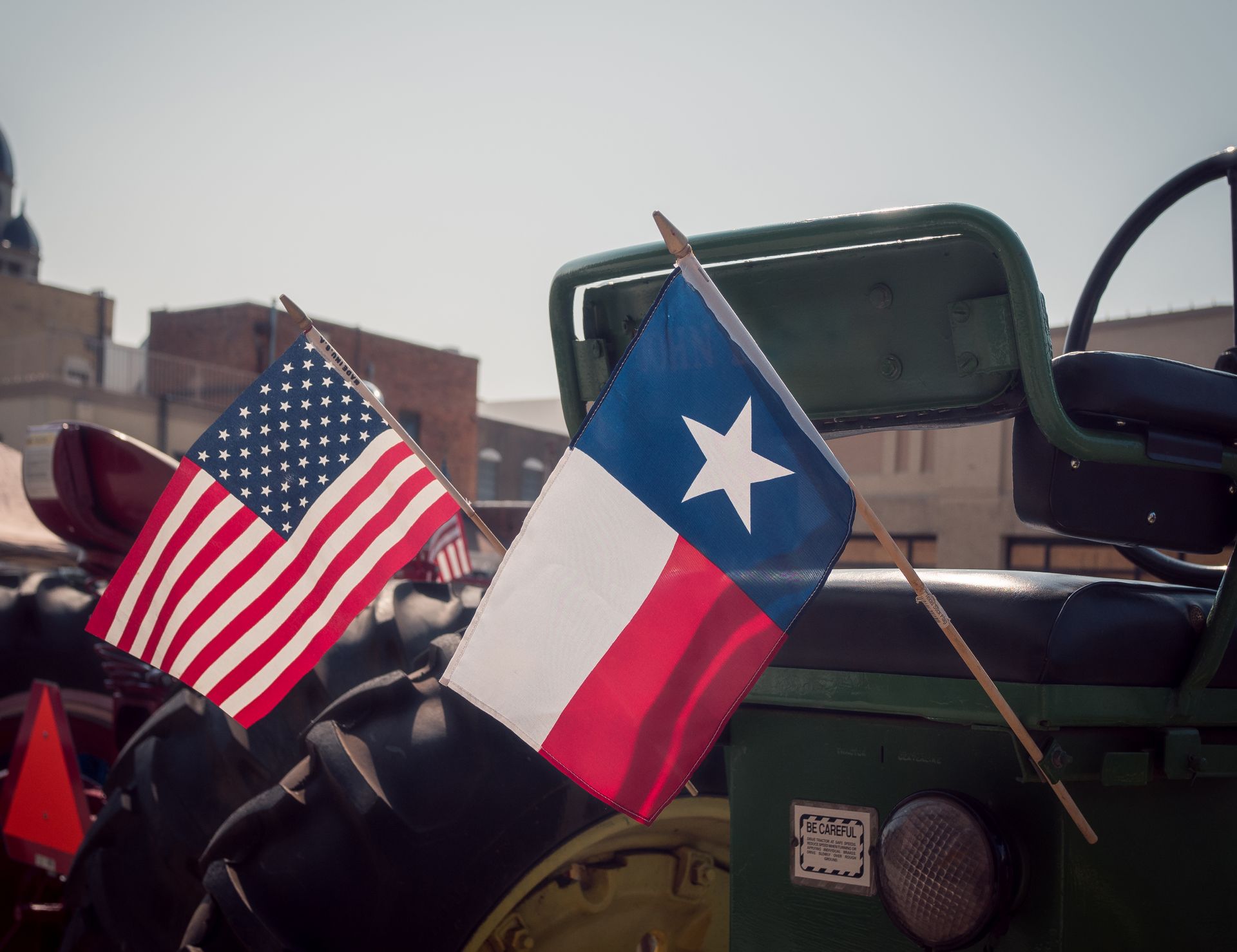An american and a texas flag are on the back of a tractor