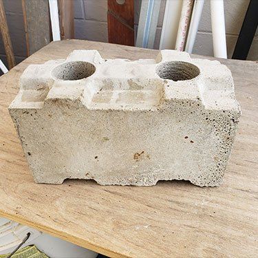 A concrete block with two holes in it is sitting on a wooden table.