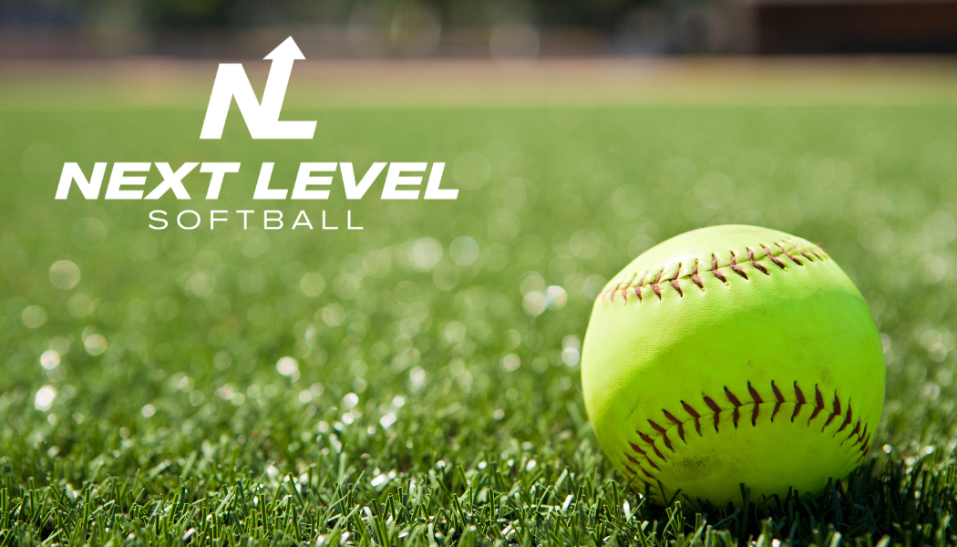 A softball is sitting on top of a lush green field.