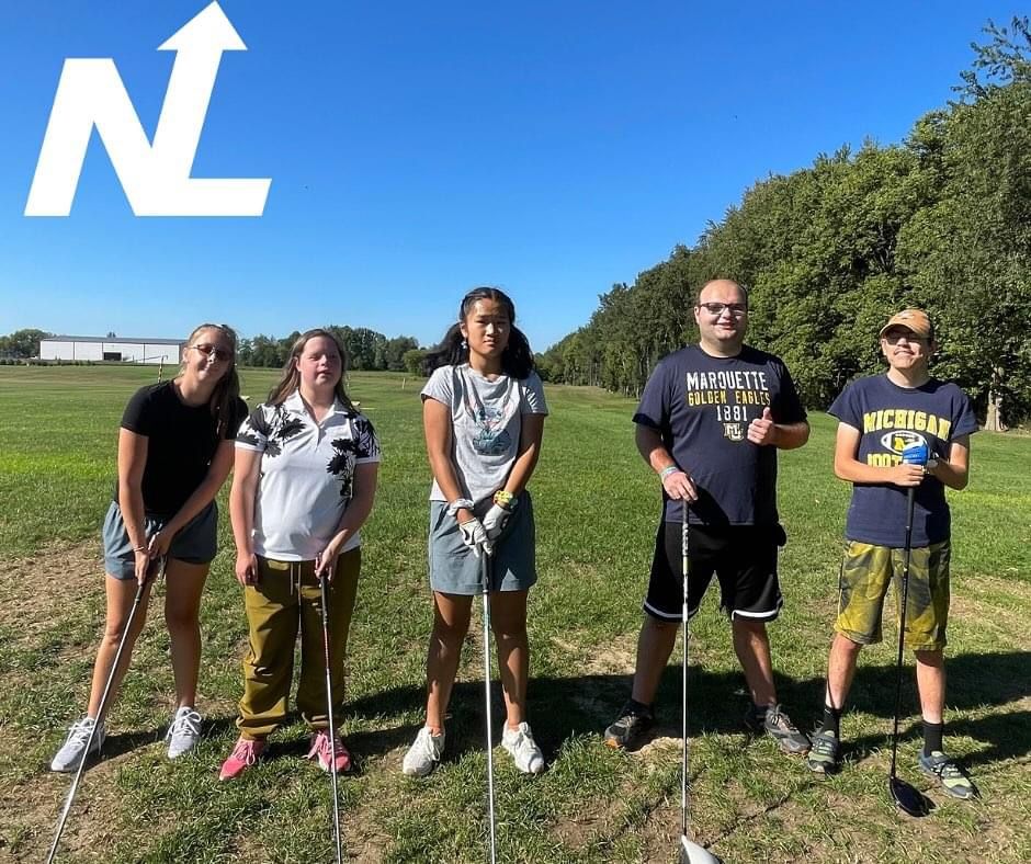 A group of people standing in a field with golf clubs