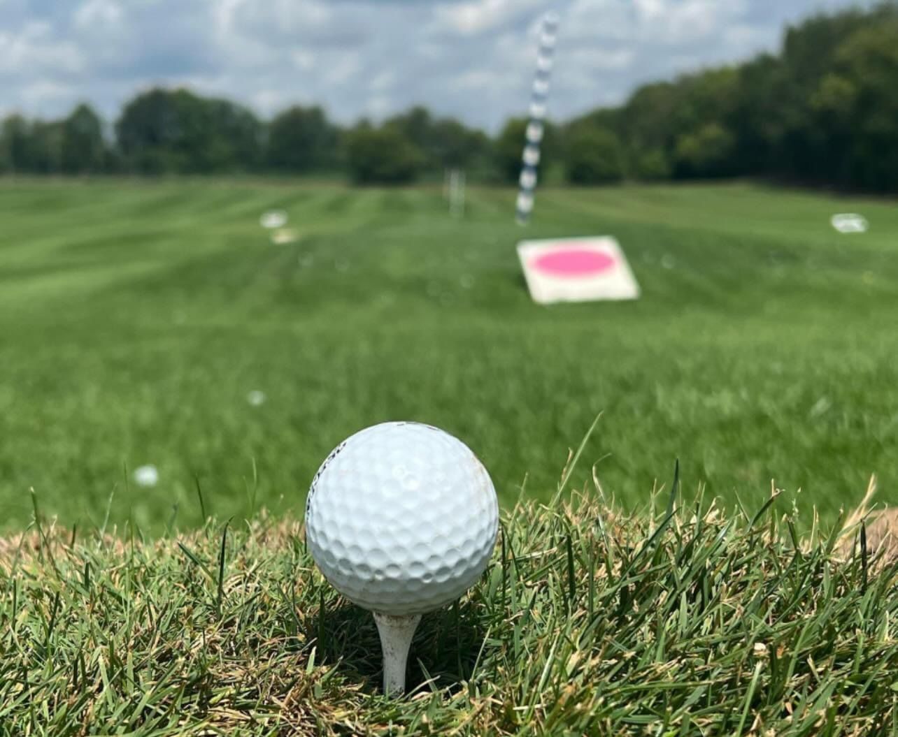 A golf ball is on a tee on a golf course.