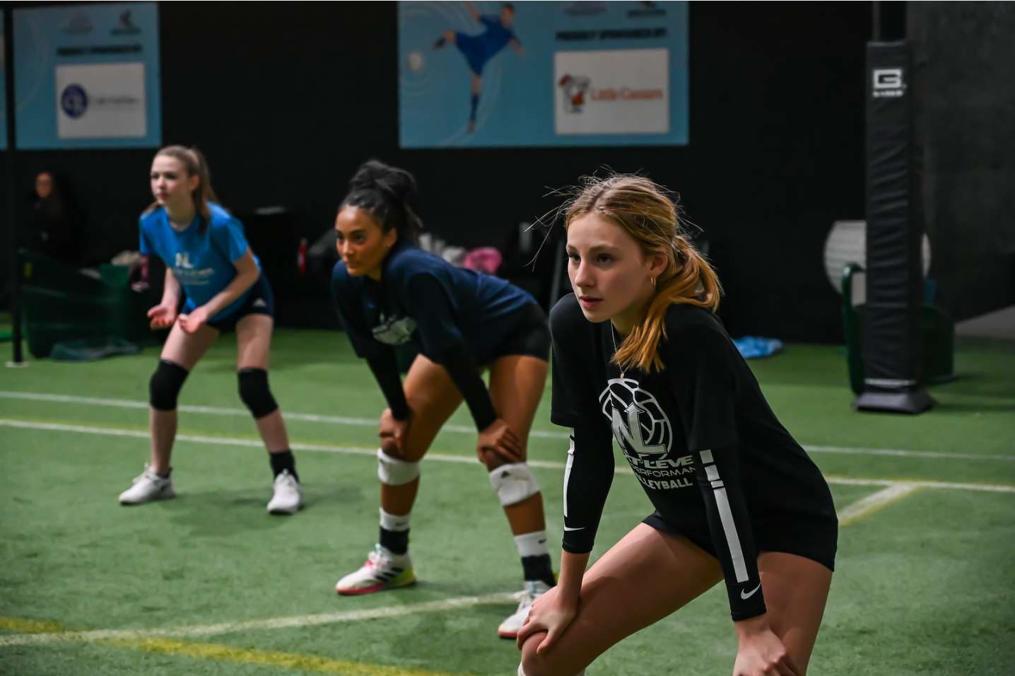 A group of young girls are playing volleyball on a field.