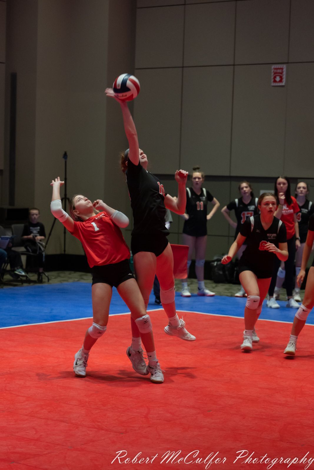 A group of girls are playing volleyball on a court.