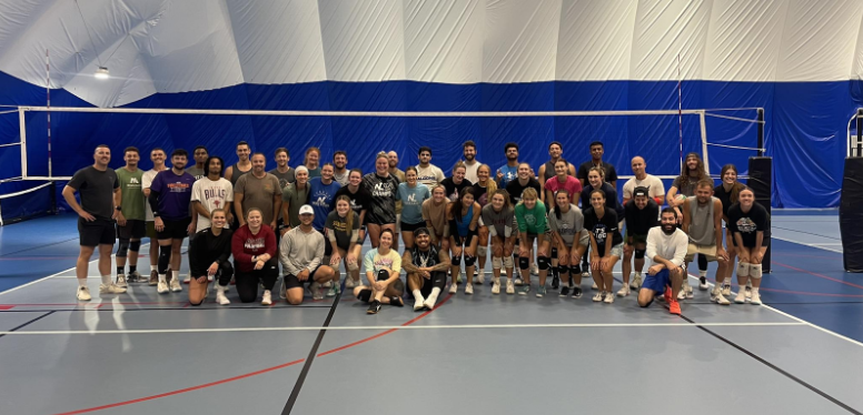Group of diverse people in a volleyball court, posing for a photo.