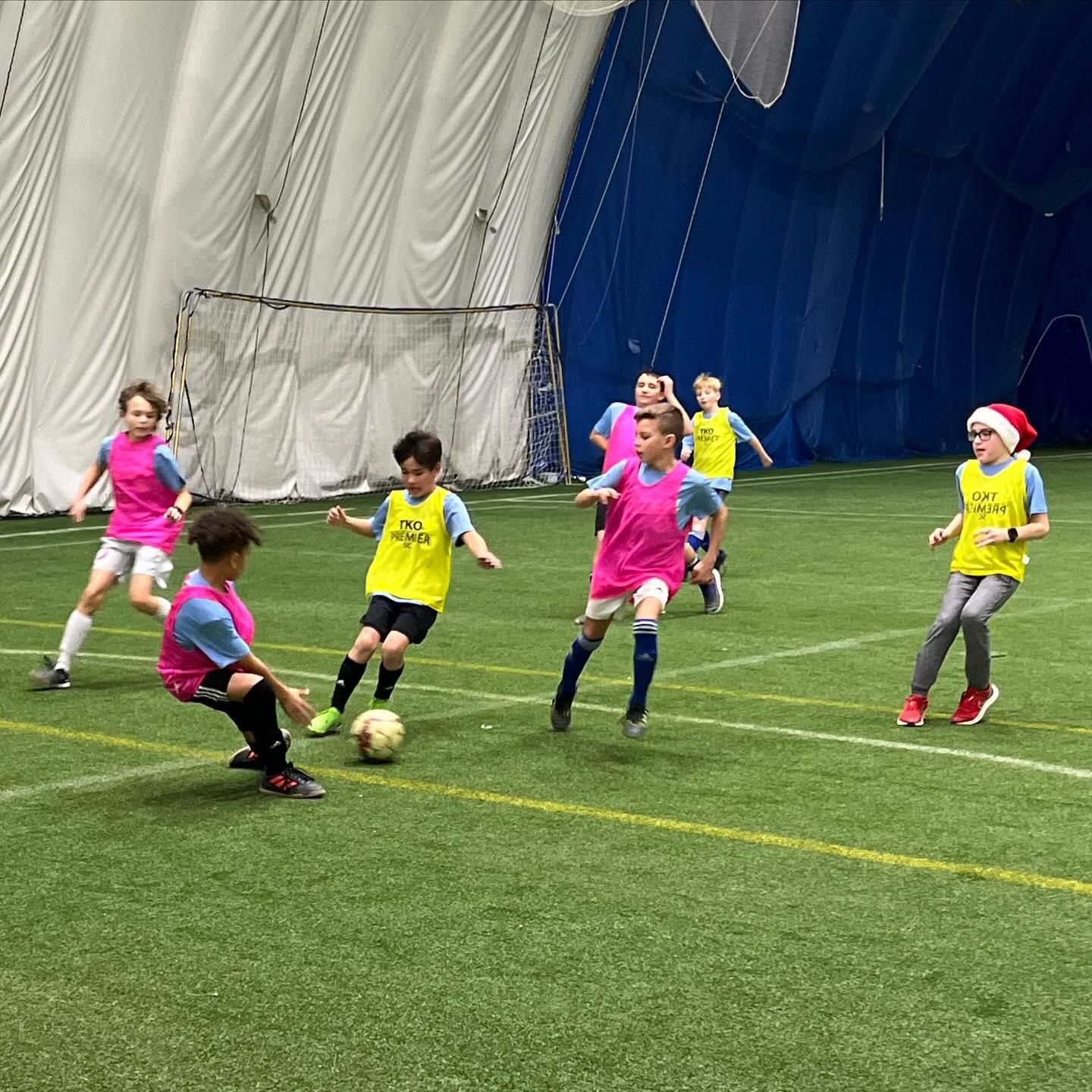 A group of young boys are playing soccer in an indoor stadium.