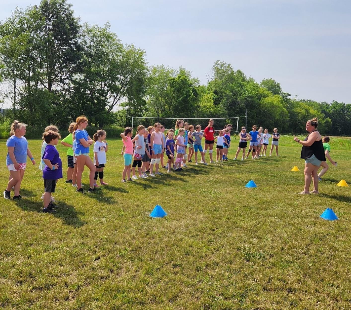 A group of children are standing in a grassy field.