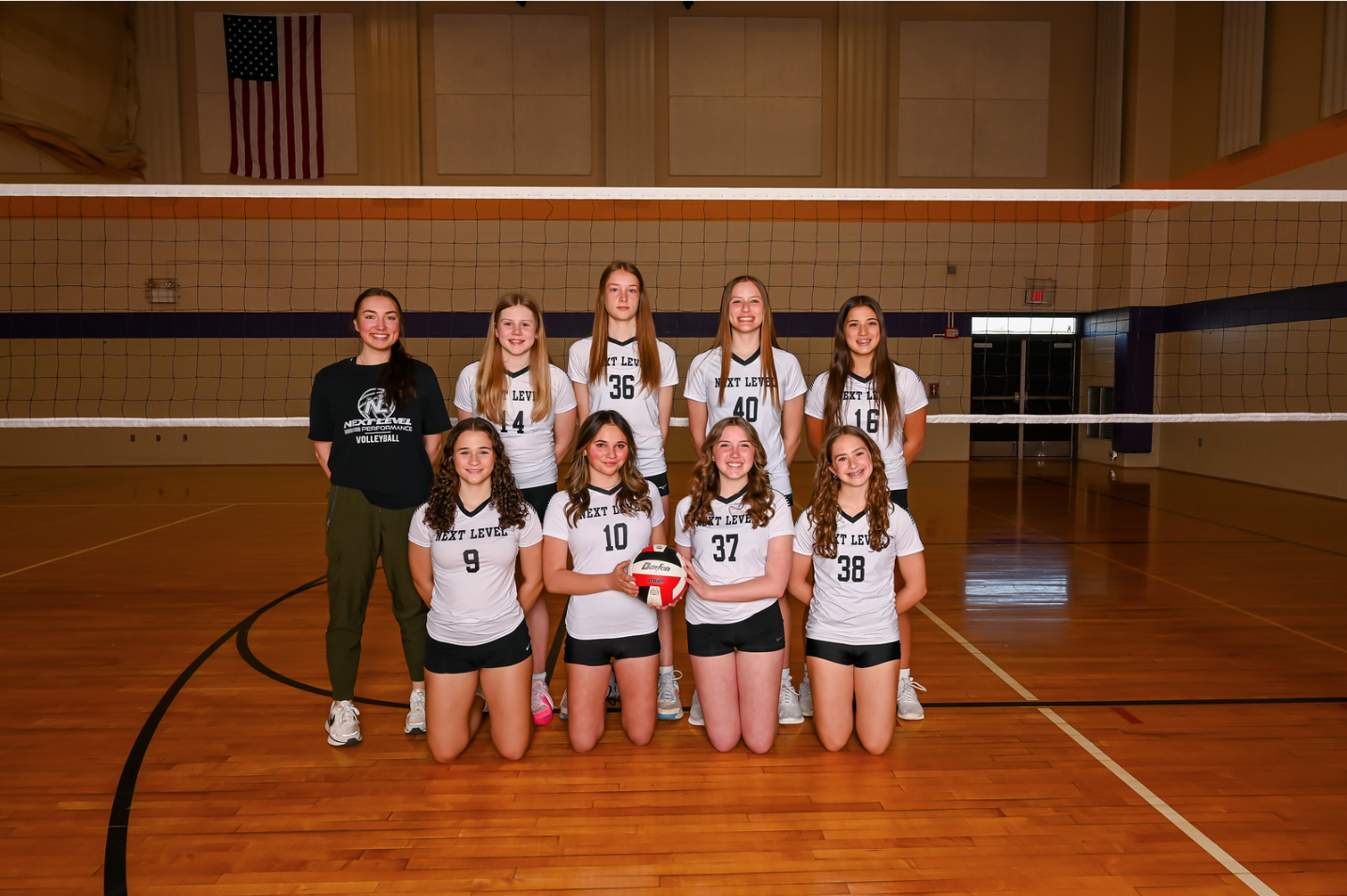 A volleyball team is posing for a picture in a gym.