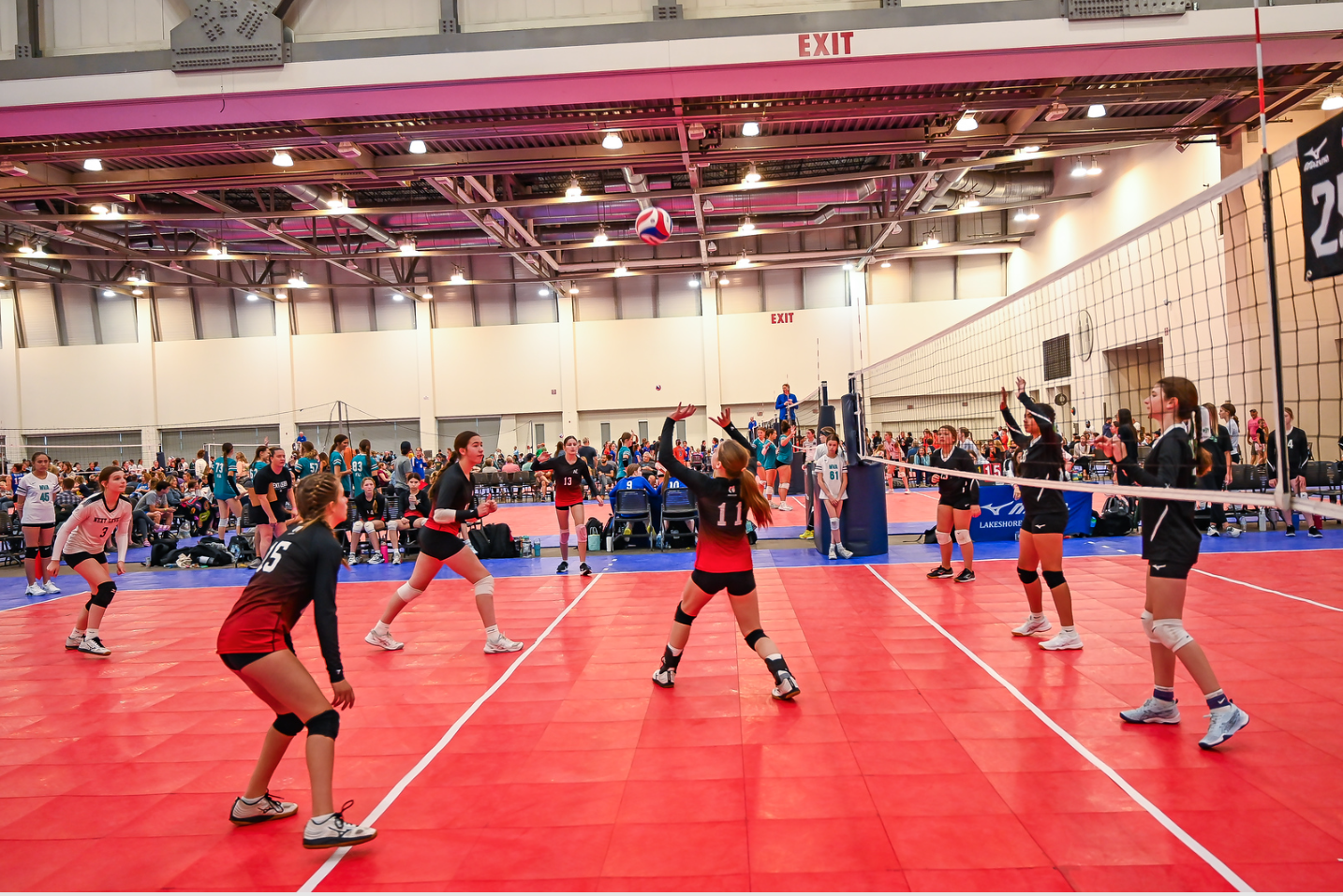 A group of women are playing volleyball in a gym.