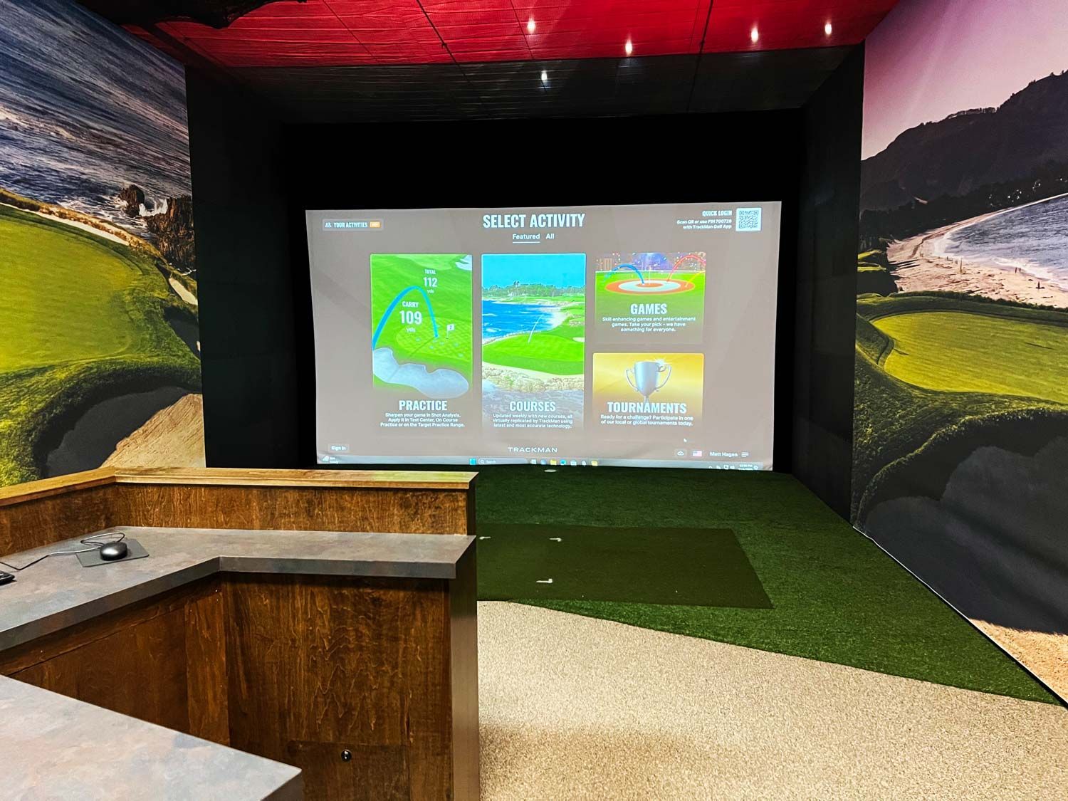 A golf simulator with a large screen on the wall.