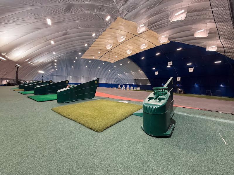 A row of golf clubs are lined up in a large indoor dome.